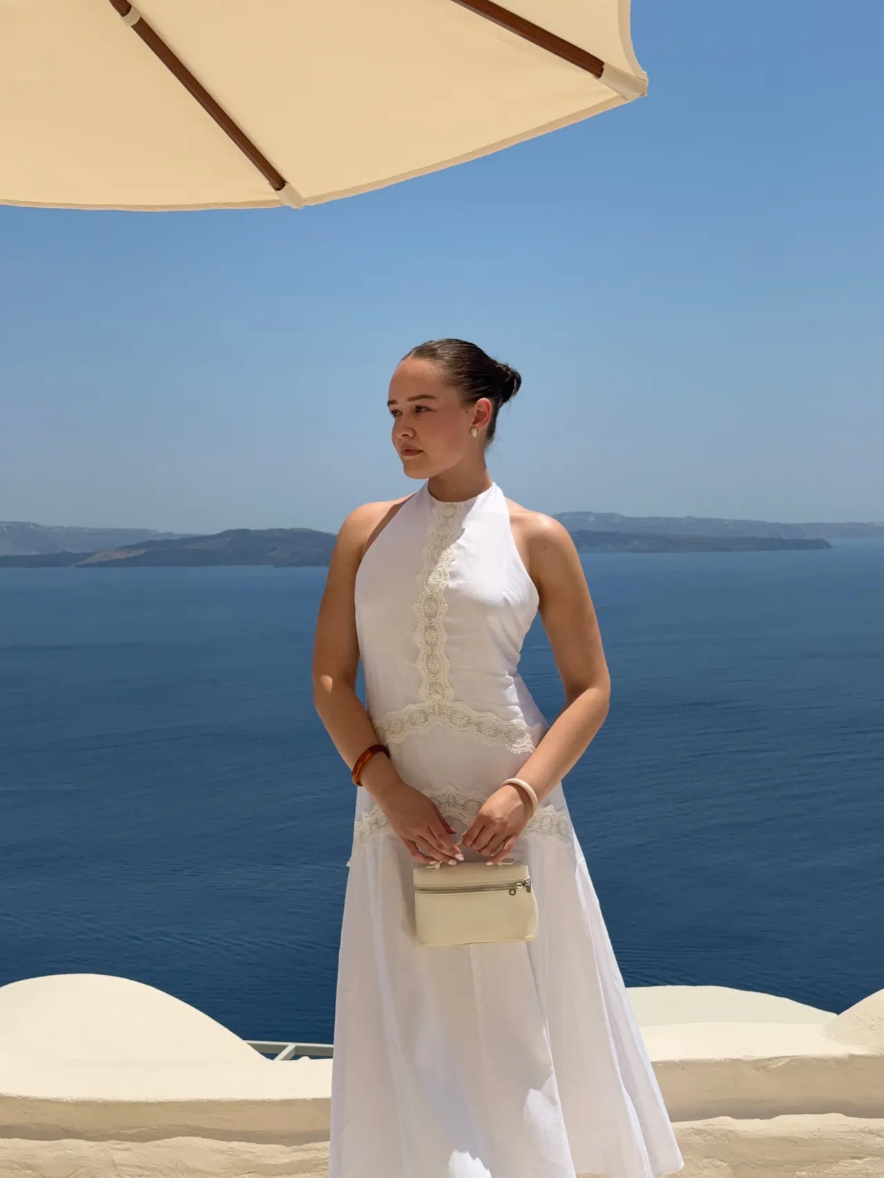 Andrea, the creator behind Love Birdie, standing against the Santorini coastline